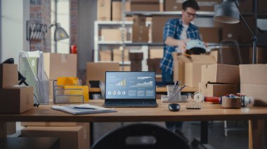 Laptop Bilgisayar Monitörü Eğilim Analiz Çizelgesi olan bir Tablo üzerinde duruyor. İşçi Arkaplanda Yürüyen Küçük İşletme Deposu