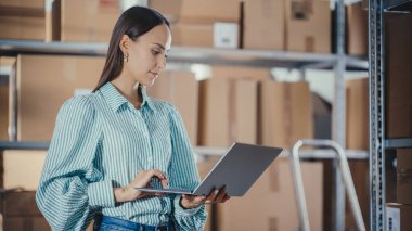 İşçi Denetleme Envanterinin Portresi, Laptop Bilgisayarına Not Yazma. Depoda Raflar dolusu rafla çalışan genç bir kadın.