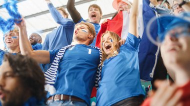 Spor Stadyumu Büyük Etkinliği: Kalabalık Mavi Futbol Takımı için tezahürat yapıyor. İnsanlar Gol Sayısı ve Şampiyonluk Zaferini Kutluyor. Sevimli Kafkas Çifti