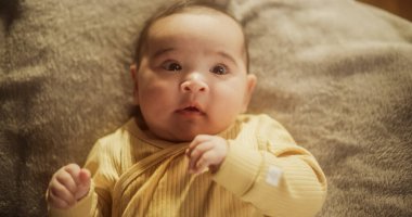 Portrait of a Cute Asian Baby Resting in a Crib, Surrounded by a Soft Blanket. Calm Baby Waking Up Under the Warm Morning Sunlight, Looking Around clipart