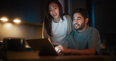 Evde Mutfakta otururken dizüstü bilgisayar kullanan genç çiftin portresi. Mutlu ve heyecanlı çift kendi küçük işletmelerini E için açıyor.