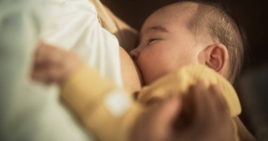 Annesi tarafından emzirilirken uyuyan şirin bebeğin portresi. Küçük bebek annesinin yanında dinleniyor. Huzuru ve huzuru hissederek sakince kucaklıyor.