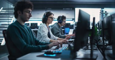 Çeşitli Çok Irklı Yazılım Geliştirme Ekibi Bilgisayarlar ve Yapay Zeka Projeleri üzerinde çalışıyor. Uzman, kulaklık takıyor.