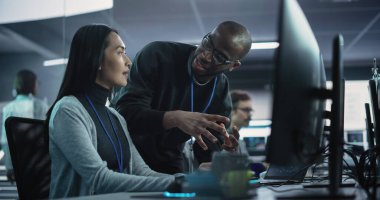 İki farklı etnik çeşitlilikte iş arkadaşı bir takım projesi üzerinde çalışırken sohbet ediyorlar. Asyalı Kadın Tasarımcı Afrika Projesi ile Konuşuyor