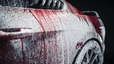 Yıkama sabunu ve köpükle kaplanmış bir Red Sport Coupe 'nin estetik çekimi. Arabanın arka çamurluğundan tekerleğe köpük damlayan yakın çekim görüntüsü
