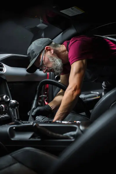 stock image Specialist Professional Car Cleaning and Detailing Company Vacuum Cleaning an Ecological Perforated Black Faux Leather Interior in a Modern Sportscar