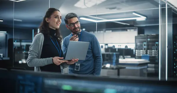 stock image Portrait of Two Happy Female and Male Engineers Using Laptop Computer to Analyze and Discuss How to Proceed with the Artificial Intelligence Software