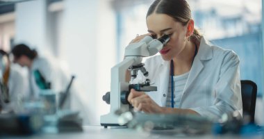 Genç Profesyonel Kadın Mühendis 'in Portresi Bir Elektrik Bileşenini İncelemek için Laboratuvarda Mikroskop Kullanıyor. Laboratuvar Olarak Çalışan Başarılı Kadın