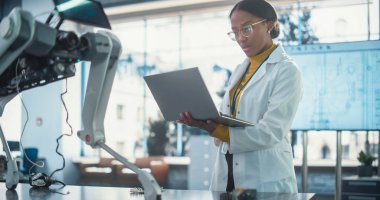 Bir yapay zeka robot prototipini test etmek için laptop kullanan genç siyah kadın laboratuvar önlüğü uzmanı portresi. Profesyonel, başarılı bir kadın olarak çalışıyor.