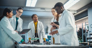 Laboratuar Önlüklü Mühendisler Laptop Bilgisayar ve Tablet kullanarak Elektronik Bileşenler için Beyin Fırtınası Fikirleri. Endüstriyel Robotik Ekibi