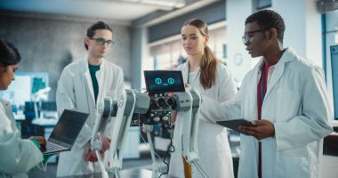 Çeşitli Endüstriyel Robot Uzmanları Mobil Robotlu Masa etrafında toplandı. Laboratuvar Önlüklü Mühendisler Otomatik Yapay Zeka Robotunu Tartışıyor