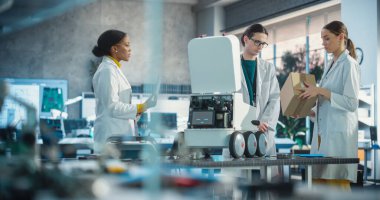 Mobil Robot üzerinde çalışan Endüstriyel Uzmanlar Ekibi bir dizüstü bilgisayar kullanıyor. Genç Erkek ve Kadın Mühendisler Bir Laboratuvarda Otomatik Yapay Zeka Robotunu Tartışıyor