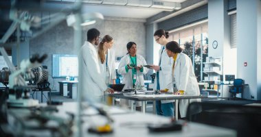 Bir grup Uluslararası Çoklu Etnik Laboratuar Uzmanı Yüksek Teknolojik Robot Projesi Planları ve Bileşenleri Tartışmak için Bir Masa etrafında toplanıyor