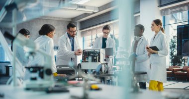 Çeşitli Endüstriyel Robot Uzmanları Mobil bir robotla bir masanın etrafında toplandı. Laboratuvar Önlüklü Mühendisler Otomatik Yapay Zeka Robotunu Tartışıyor