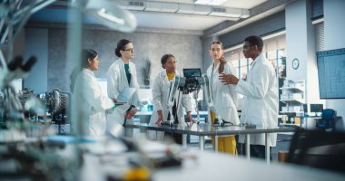 Profesyonel Uluslararası Genç Kadın ve Erkek Mühendisler Takımı Fabrika Geliştirme Atölyesinde Endüstriyel AI Robot Köpeğini Tartışıyor. Teknoloji Tesisi