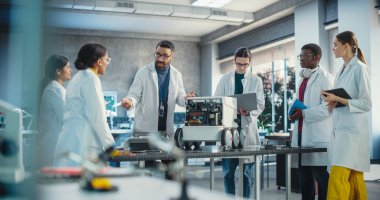 Çeşitli Endüstriyel Robot Uzmanları Mobil bir robotla bir masanın etrafında toplandı. Laboratuvar Önlüklü Mühendisler Otomatik Yapay Zeka Robotunu Tartışıyor