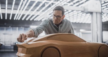 Araba Modelleyicisi, Plastik Modelleme Clay 'den yapılmış bir konsept araba üzerinde yaratıcı çalışma sürecinin tadını çıkarıyor. Yakışıklı Tasarımcı Spatula ile Pürüzsüz