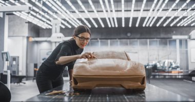 Kadın Otomotiv Tasarımcısı Polymer Modelleme Clay 'den bir prototip araba yaratmak için bir Spatula kullanıyor. Araştırma ve Geliştirmede Odaklanmış Modelleyici
