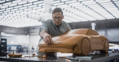 Yakışıklı bir Otomotiv Tasarımcısının Portresi Yeni Bir Yapım Arabasının 3 boyutlu Clay Modelini Geliştiriyor. Profesyonel Yetişkin Adam Yumuşatmak için Spatula Kullanıyor