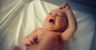 Bir doğum hastanesinde beşiğinde yatan şirin, küçük, beyaz bir bebek. Minik, neşeli ve enerjik bir çocuğun portresi. Sağlık, Hamilelik