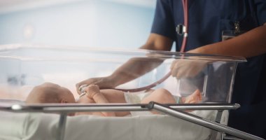 Doğum Hastanesi Koğuşu: Dost canlısı Siyah Baş Hemşire Yatakta İyileşen Yeni Doğan Bebeğin Kalp atışlarını ve Ciğerlerini Dinlemek İçin Steteskop Kullanıyor
