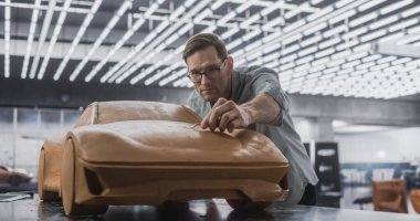 Plastikten yapılmış konsept bir araba üzerinde çalışan İskandinav görünümlü bir araba modelinin portresi. Yetişkin Tasarımcı Yumuşak Spatula Kullanıyor