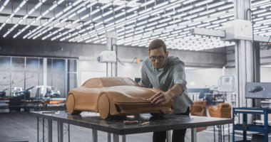 Gözlüklü Yakışıklı Otomotiv Tasarımcısı Polymer 'dan çıkan bir prototip araba üzerinde çalışıyor Clay' i modelliyor. Modelci Yüzeyde Heykel Yapıyor, Üç Boyutu Düşünüyor