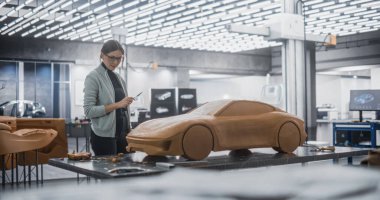 Kadın Otomotiv Tasarımcısı Polymer Modelleme Clay 'den bir prototip araba yaratmak için bir Spatula kullanıyor. Odaklanmış Modelleyici Bir Araştırma ve