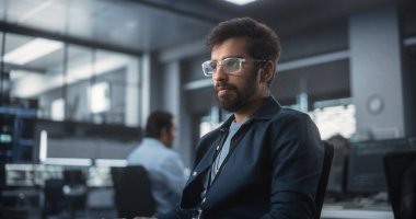 Teknolojik bir laboratuvar ortamında bilgisayar üzerinde çalışan yakışıklı bir Hint yazılım geliştiricisi. Genç adam işyerinde düşünceli, taslak çiziyor.