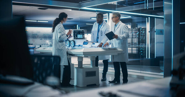 Команда инженеров-технологов, работающих над роботом мобильности на пусковом заводе. Мультиэтнические ученые мужского и женского пола обсуждают автоматизированный ИИ