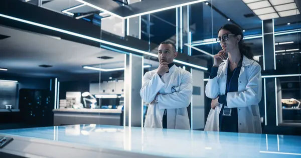 stock image Multiethnic Male And Female Scientists Standing In the High-Tech Laboratory Next to The Table. Professional Industrial Engineers Gesturing Over The