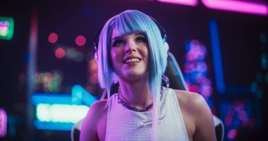 Gülümseyen Kostümcü Kız, Gelecekçi Siberpunk Neon Home 'da otururken Online Arkadaşlarıyla Masaüstü Bilgisayarında Konuşuyor. İnternet Oynayan Genç Kadın
