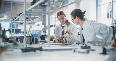 Güvenlik Gözlükleri ve Beyaz Önlüklü Kadın ve Erkek Öğrenciler Bilim Sınıfında Birlikte Çalışıyor, Bir Üniversite Projesinde İşbirliği Yapıyorlar. Bilginler konuşuyor