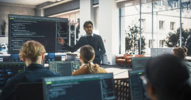 Üniversite odasında çeşitli etnik çeşitlilikteki kadın ve erkek öğrencilere bilgisayar bilimi dersi veren öğretmen. Slayt Gösterisi Bununla Projeleniyor