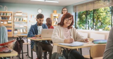 Çeşitli Olgun Öğrenciler Sınıfta Öğreniyor, Dizüstü bilgisayar kullanıyor ve Not Defteri Yazıyor. Yetişkinlikte Yeni Yetenekler Öğrenmek İçin Kıdemli Kadın Motive Edildi