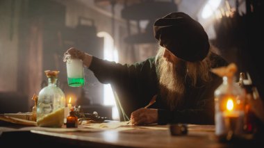 Fantezi Ayarlama: Ortaçağ Laboratuvarında İksir üzerine çalışan Bir Simyacının Portresi, Not Almak. Şifa İksiri Oluşturan Yaşlı Büyücü