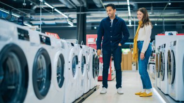 Genç Çok Irklı Çift Çamaşır Makinesi Seçimi İçin Ev Elektronik Mağazasını Keşfetti. Çamaşır Aletleri için İkili Alışveriş. Müşteriler Modern Değerlendirme
