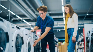 Bir Perakende Elektronik Dükkanı Danışmanı 'nın portresi. Evi için Çamaşır Makinesi Seçimi' nde Genç Bir Kadın Müşteriye Yardım Ediyor. Güzel Dişi