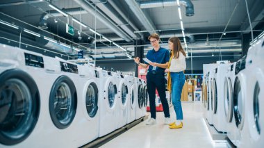 Genç Bayan Müşteri Çamaşır Makinesi Seçerken Ev Elektronik Mağazası İşbirlikçisi ile İş Yapıyor. Şık Kadın Yüksek Kaliteli Alet Arıyor