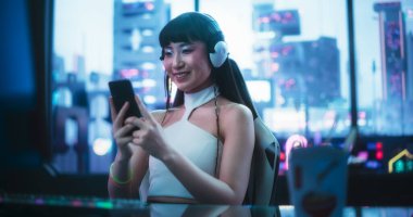 Güzel gülümseyen Asyalı Kadın Akıllı Telefon Kullanırken Gelecekçi Siberpunk Ofis Alanında Masa Arkasında Oturuyor. Genç Japon Kadın...