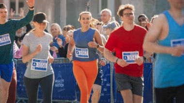 Bir maratona katılan ve şehir yolunda koşan bir grup insanın portresi. Koşucular bitiş çizgisine ulaşmak için ellerinden geleni yapıyorlar.