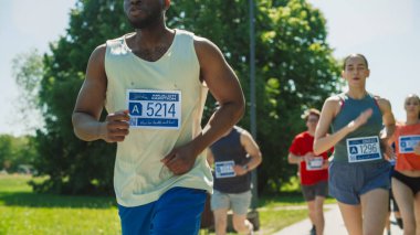 Green Park Trail 'de gündüz vakti bir şehirde Maraton koşan Siyah Atletik Bir Erkeğin Yakın Portresi. Dayanıklı ve adanmış koşucular