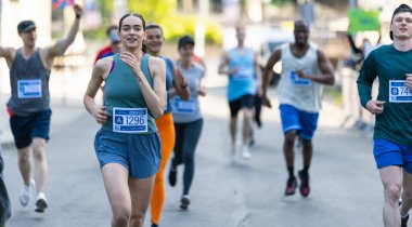 Gün boyunca bir şehirde maraton koşan çeşitli insanlar grubu. Etkin ve Uygun Gülümseyen Kadın Koşucu Bitiş Çizgisine Ulaşmak İçin Yarışıyor