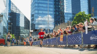 Şehirdeki bir maraton yarışında yarışan çeşitli insan grupları. Seyircilerin Aile ve Arkadaşları Hevesle tezahürat yapıyor ve destekliyor