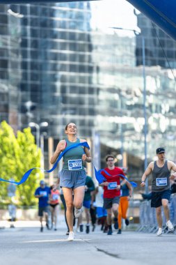 Seyirciyle Maraton Yarışı bitiş çizgisini geçen atletik bayan koşucunun portresi. Kazananı Kutlayan Başarılı Kadın