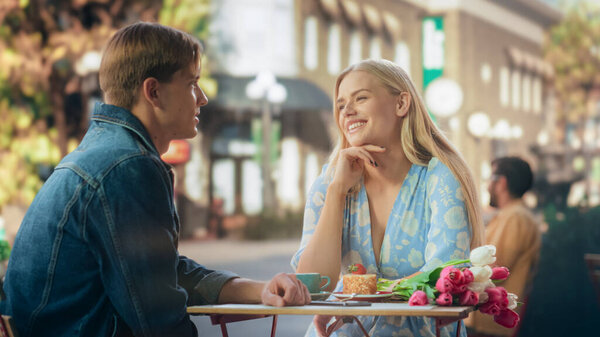 Любимая парочка за романтическим обедом в кафе на открытом воздухе. Красивый молодой человек берет обручальное кольцо и делает предложение своей прекрасной любимой