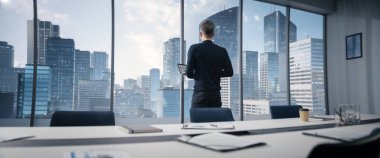 Kafkasyalı İşadamı Megapolis City View ile Köşedeki Ofise Gidiyor, Bilgisayarı elinde tutuyor. Profesyonel CEO Büyük Pencere 'nin önünde duruyor