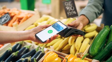 Dijital Bankacılık Konsepti: Alışverişçinin Çiftçi Marketinde Doğal Ürünlerin Ödenmesi İçin Temassız Ödeme Teknolojisi ile Cep Telefonu Kullanması. Sokak Satıcısı