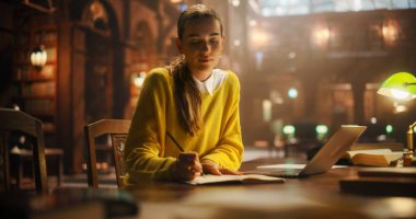 Klasik Kütüphanede Çalışan Genç Kadın, Kitaplarla çevrili, Not Defterinde Araştırma ve Yazma İçin Dizüstü Bilgisayar Kullanılıyor. Sakin Akademik Ayarlar