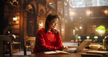 Klasik Kütüphanede Çalışmak İçin Dizüstü bilgisayar kullanan çok ırklı Asya Koleji Öğrencisi. Güzel Genç Kadın İnternette Öğreniyor, Hazırlanıyor